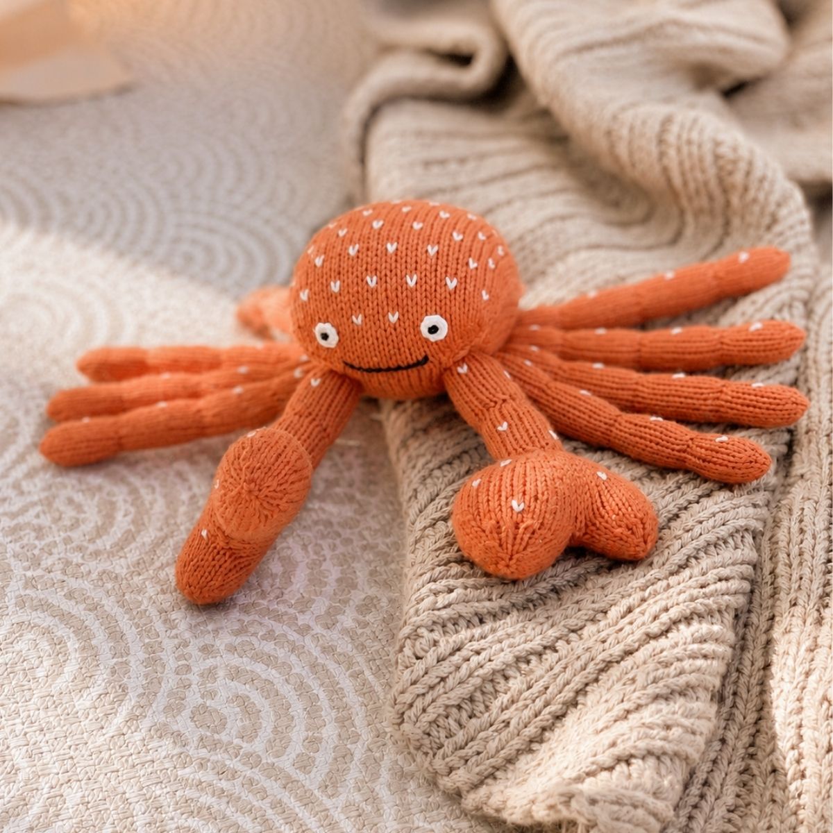 Kuscheltier Krebs aus Bio-Baumwolle auf einer weichen Decke – handgestricktes Kuscheltier für Babys und Kinder