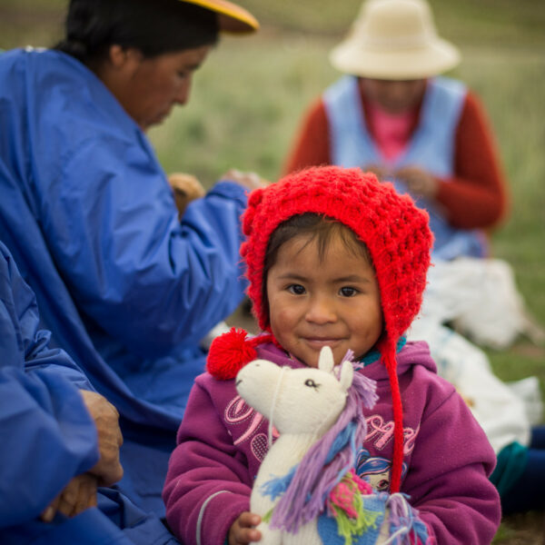 Peruanisches Mädchen hält Kuscheltier Einhorn in Händen das seine Mama gestrickt hat
