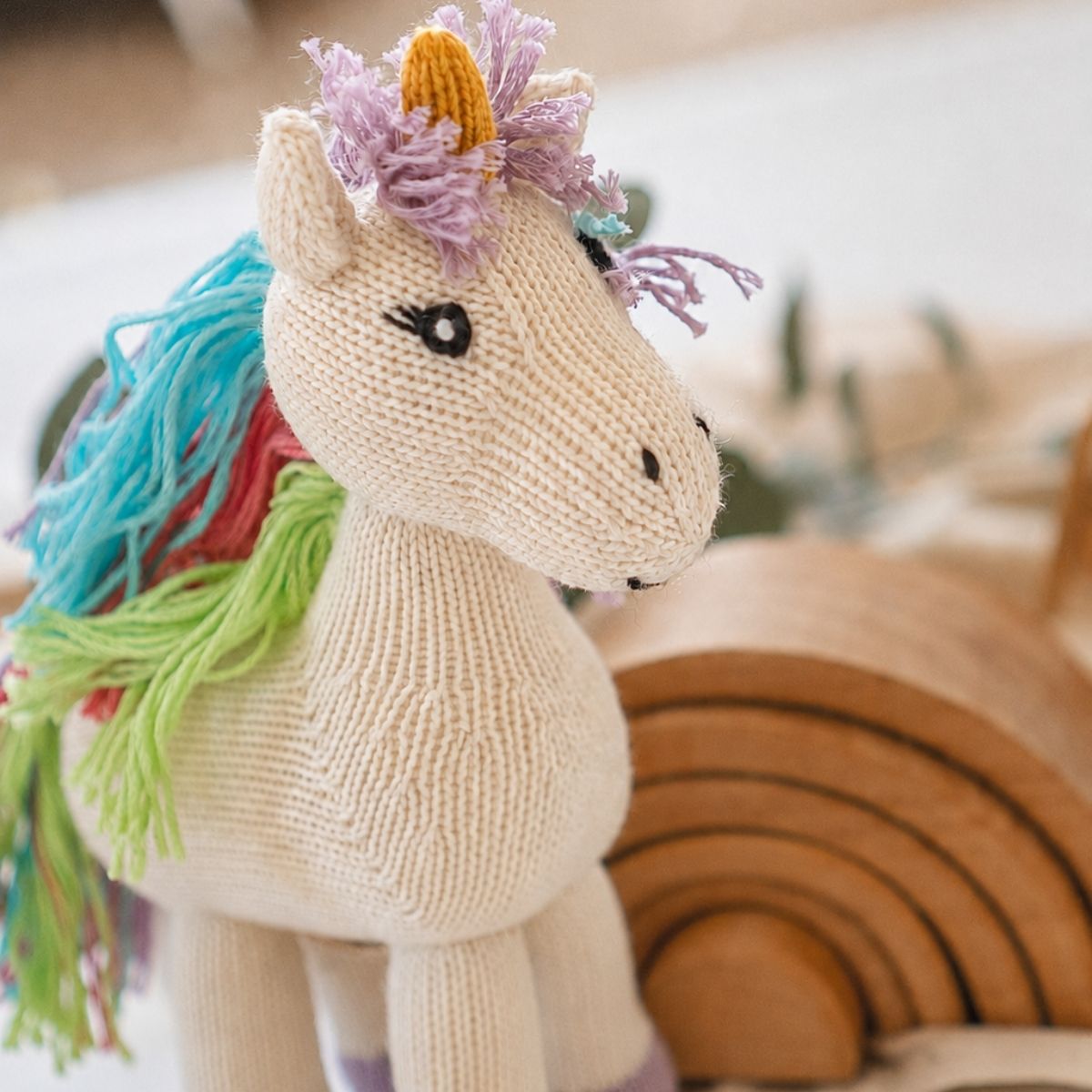 Handgemachtes Bio Kuscheltier Einhorn aus Baumwolle mit buntem Garnhaar, gestricktem Horn und lilafarbenen Hufen