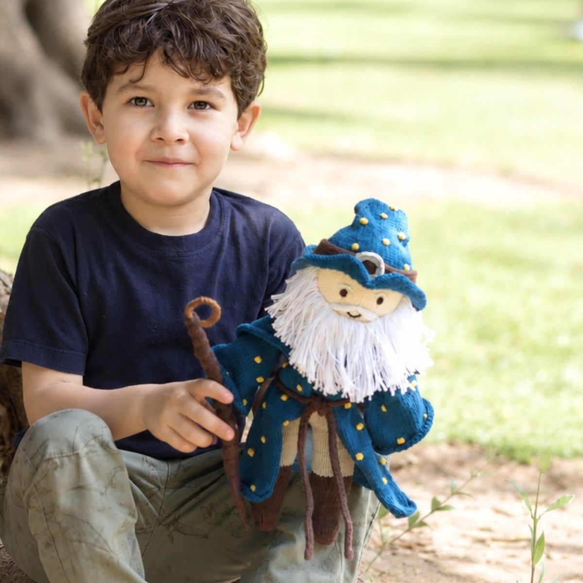 Kind hält eine handgestrickte Zauberer Puppe aus Bio-Baumwolle im Arm und spielt im Park