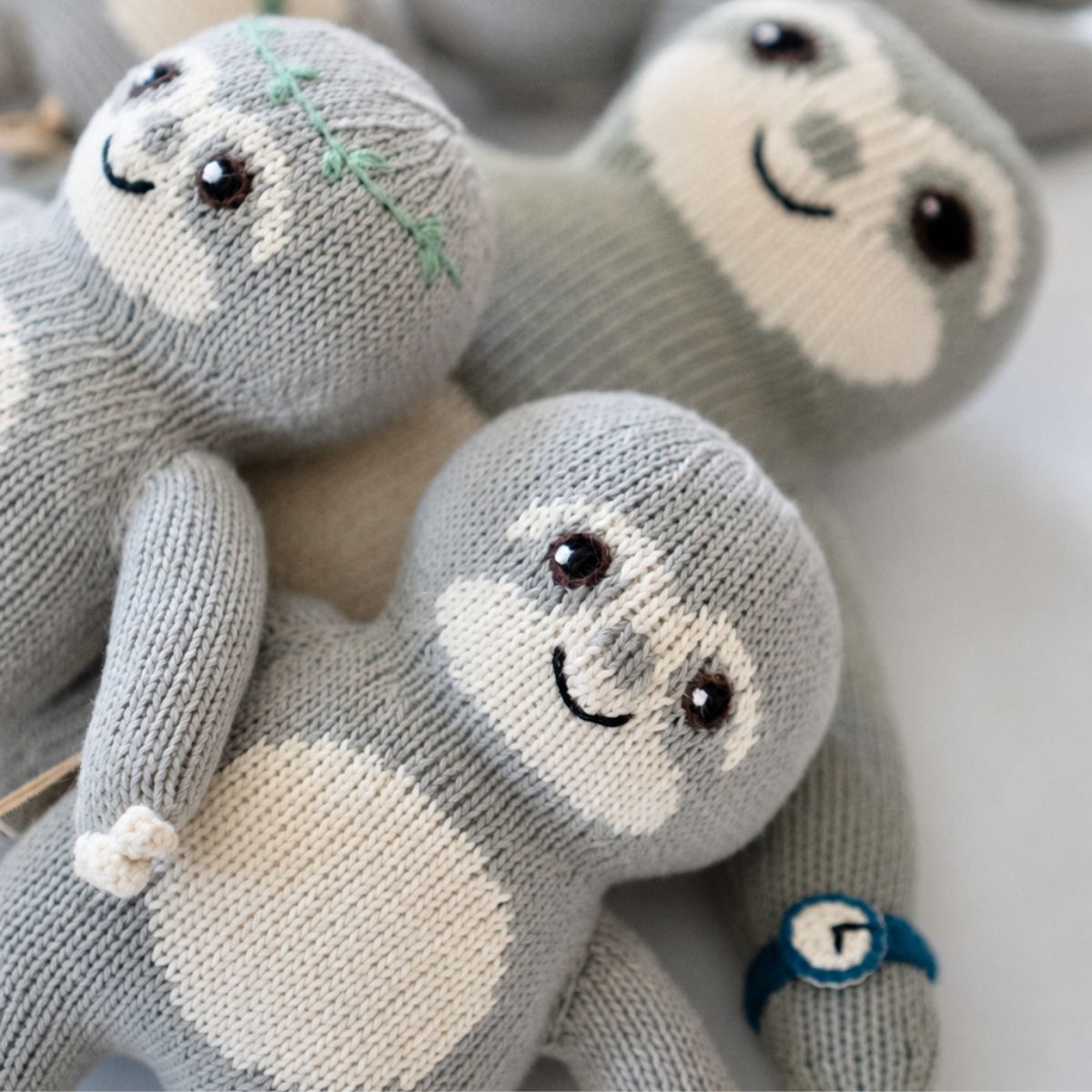 Schlichtes Baby Faultier ohne Stickerei zwischen verschiedenen handgemachten Glücksfaulis aus Bio-Baumwolle