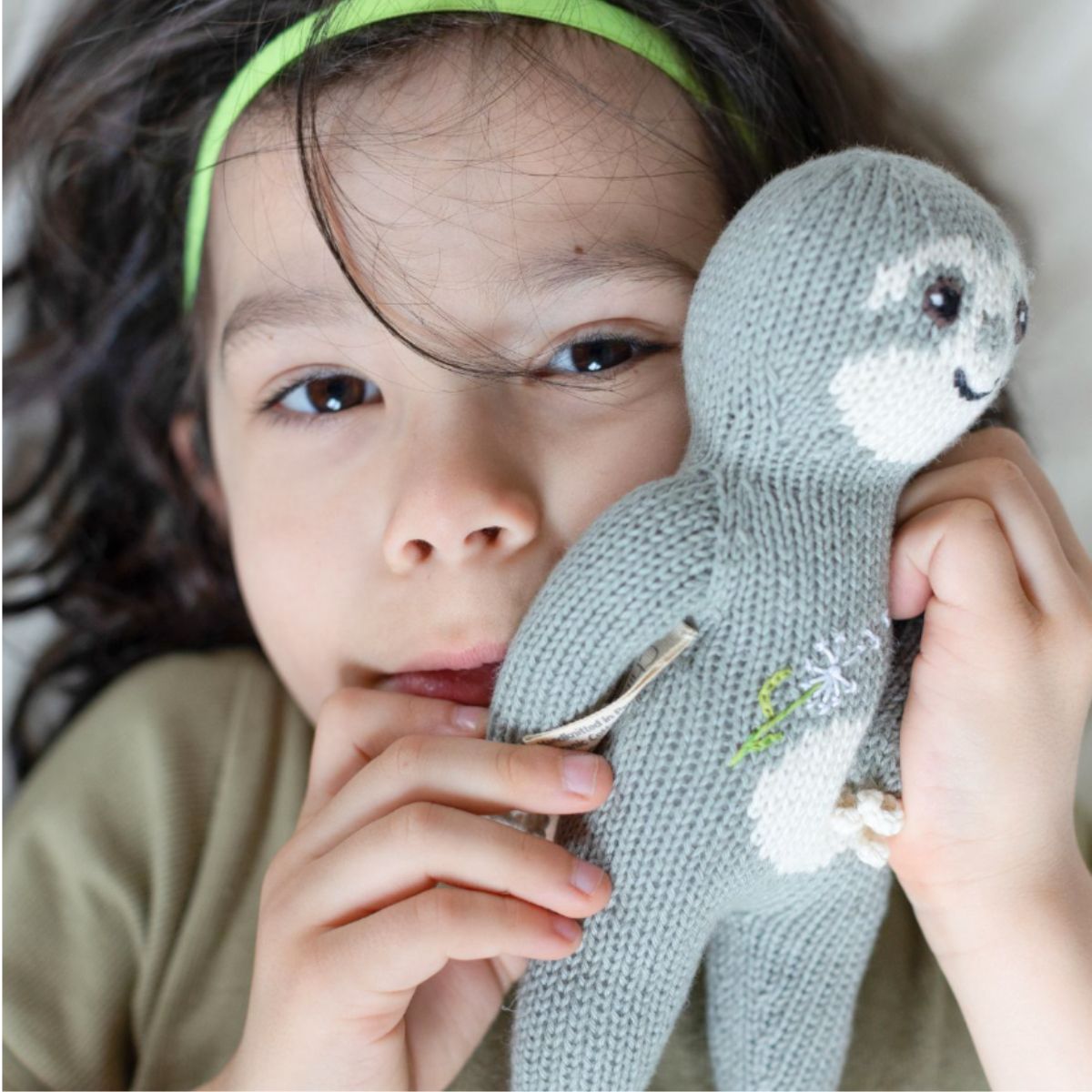 Kind hält das Bio Kuscheltier Wunschkind mit Pusteblume liebevoll an der Wange