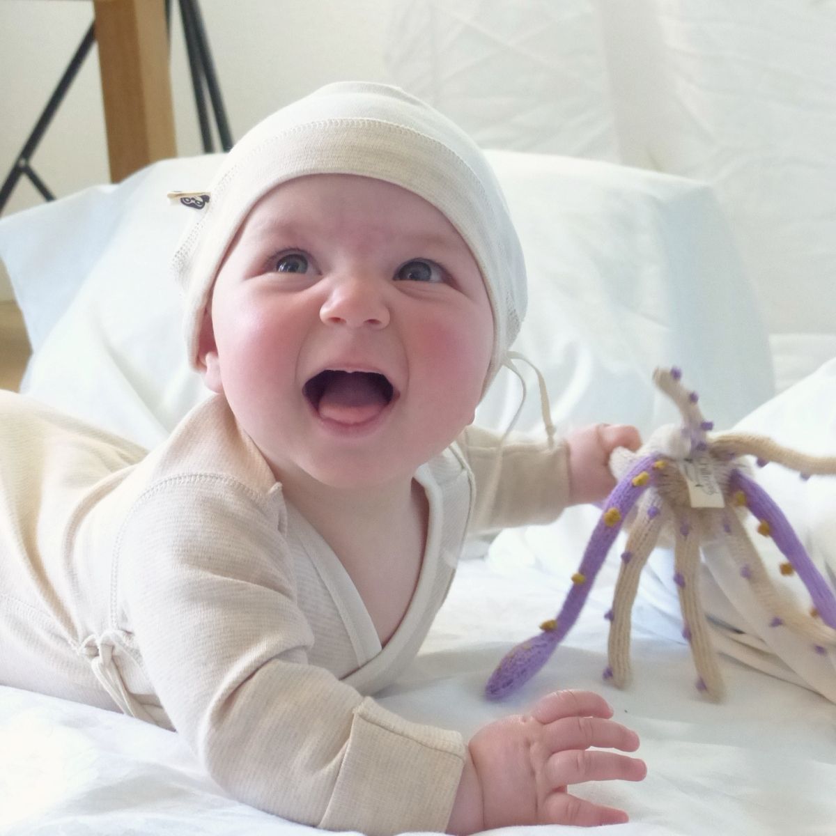 Baby spielt mit Bio Kuscheltier Kalmar aus weicher Baumwolle