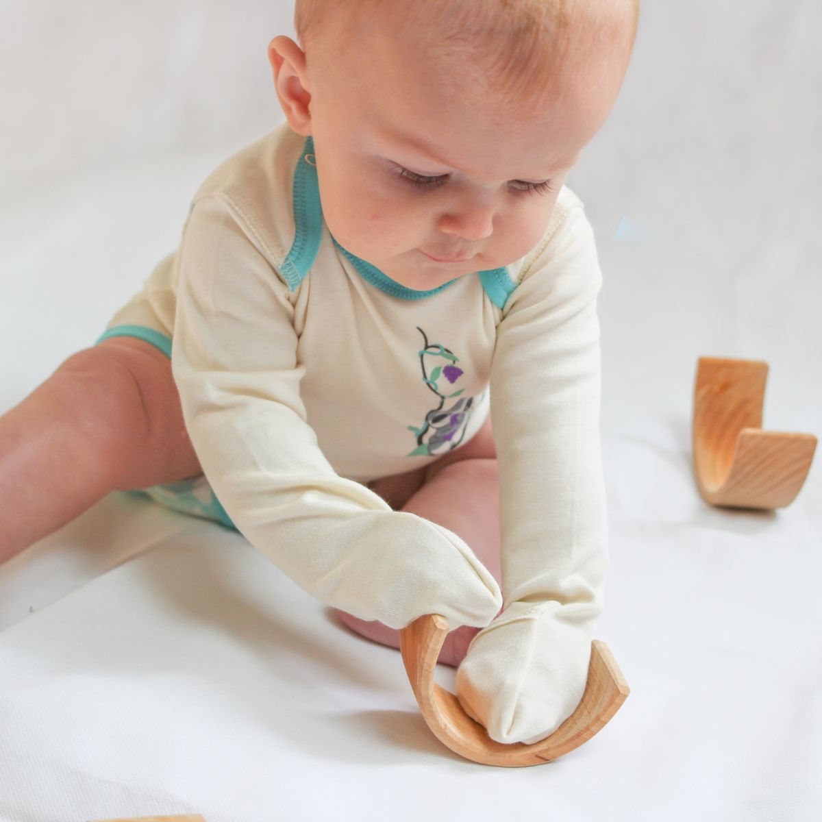 Baby spielt mit dem Kratzschutz am Body, ideal bei Neurodermitis und empfindlicher Haut.