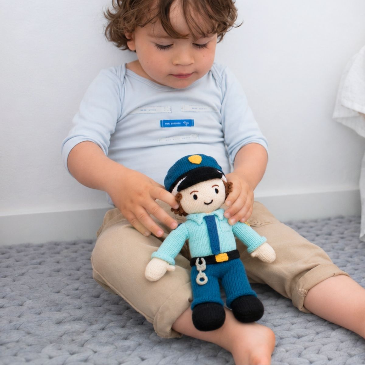 Kind spielt mit einer handgestrickten Puppe Polizist aus Bio-Baumwolle von Chill n Feel.