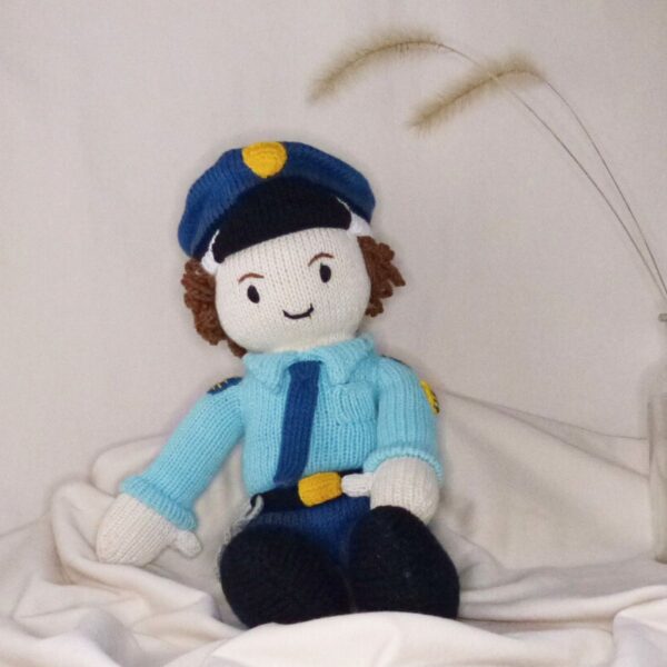 Handgestrickte Puppe als Polizist mit blauer Uniform auf hellem Hintergrund