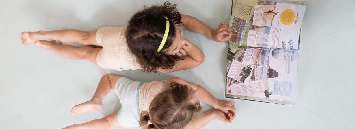 Einschlafrituale für Kleinkinder: Zwei Kinder schauen gemeinsam ein Buch an und lassen den Tag in ruhiger Atmosphäre ausklingen.