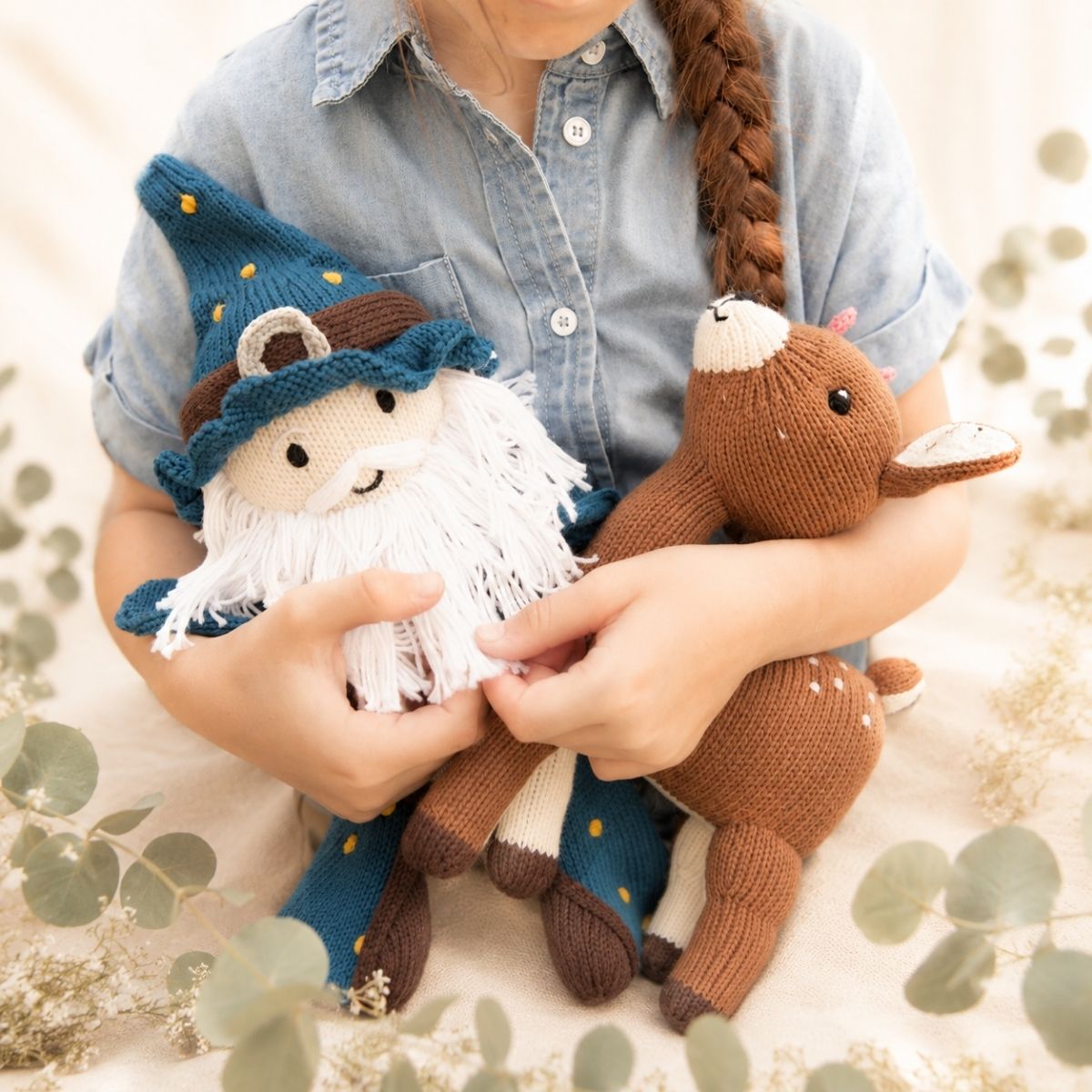 Kind kuschelt handgestrickten Zauberer und Reh aus Bio-Baumwolle – liebevolles Geschenk zur Geburt für Baby und Geschwister
