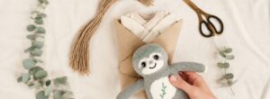 Babygeschenke verpacken mit handgestricktem Faultier, Bio Babybody, Packpapier und Eukalyptus