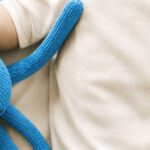 Baby in leichter Kleidung mit blauem Oktopus – Babyschlaf im Sommer bei heißen Nächten