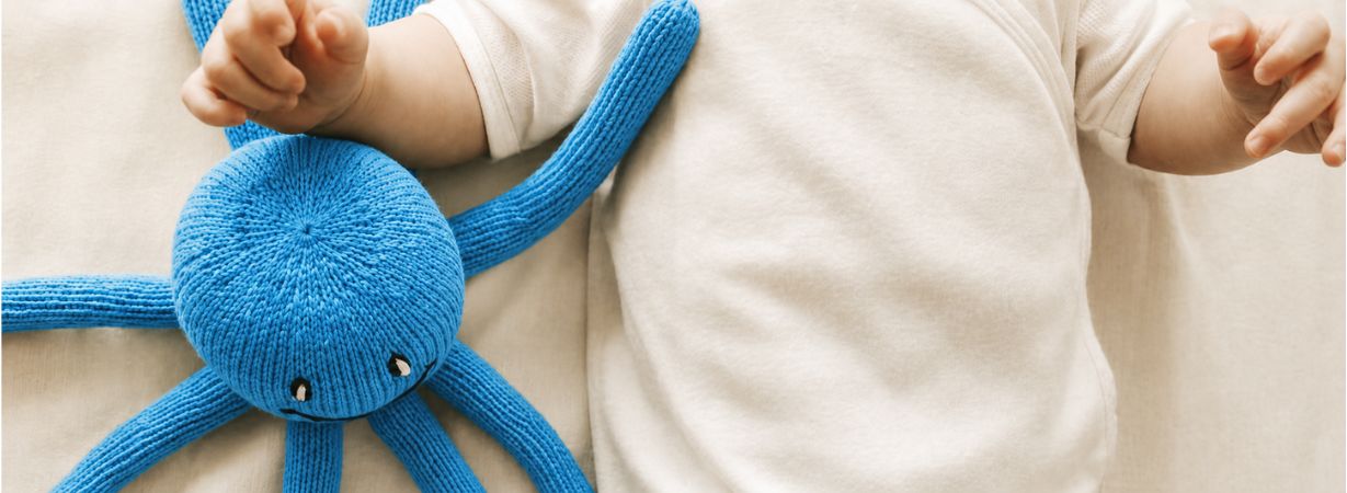 Baby in leichter Kleidung mit blauem Oktopus – Babyschlaf im Sommer bei heißen Nächten