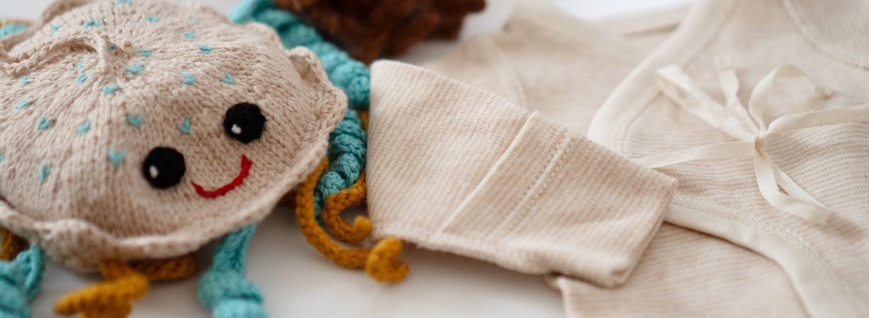 Gestrickte Qualle mit bunten Tentakeln und beige Frühchenkleidung aus Bio-Baumwolle – liebevoll ausgewählte Geschenke für Frühchen.