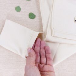 Detailansicht der Neurodermitis Hose in Natur – Hand zeigt umklappbaren Kratzschutz am Hosenbein aus weicher Bio-Baumwolle.