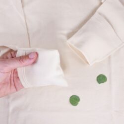 Detailansicht Neurodermitis Langarmshirt in Natur – umklappbarer Kratzschutz am Ärmel wird mit der Hand demonstriert.