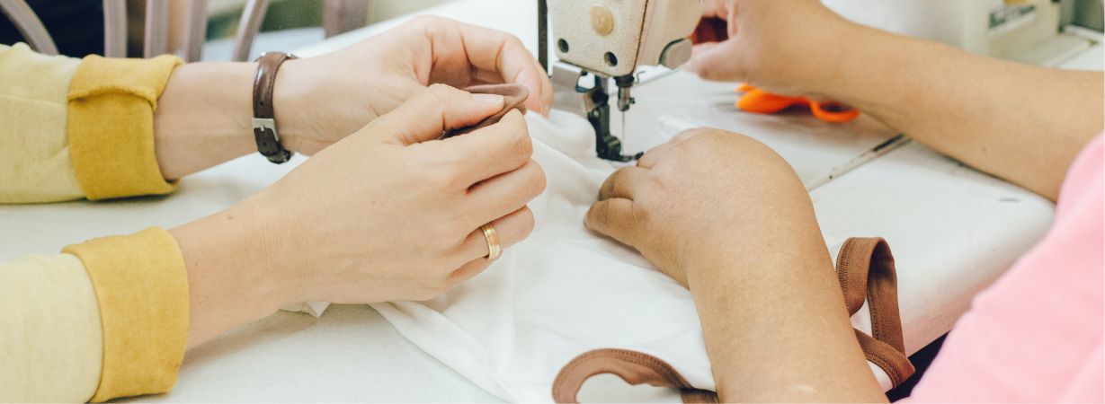 Hände stellen hautberuhigende Kleidung für Kinder mit Hand Neurodermitis her, die speziell für empfindliche Haut entwickelt wurde.