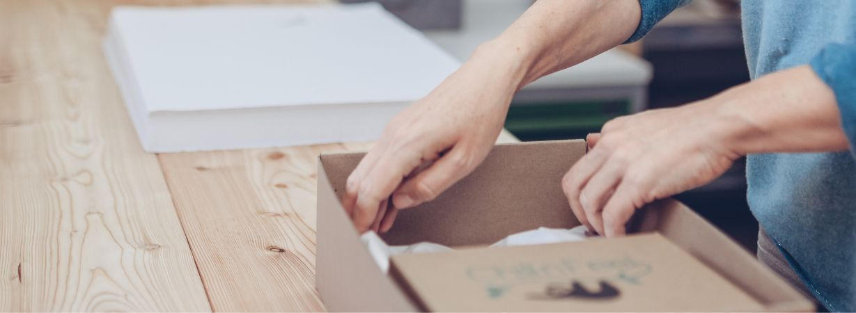 Hände verpacken ein Kuscheltier von Chill n Feel liebevoll in eine nachhaltige Geschenkbox