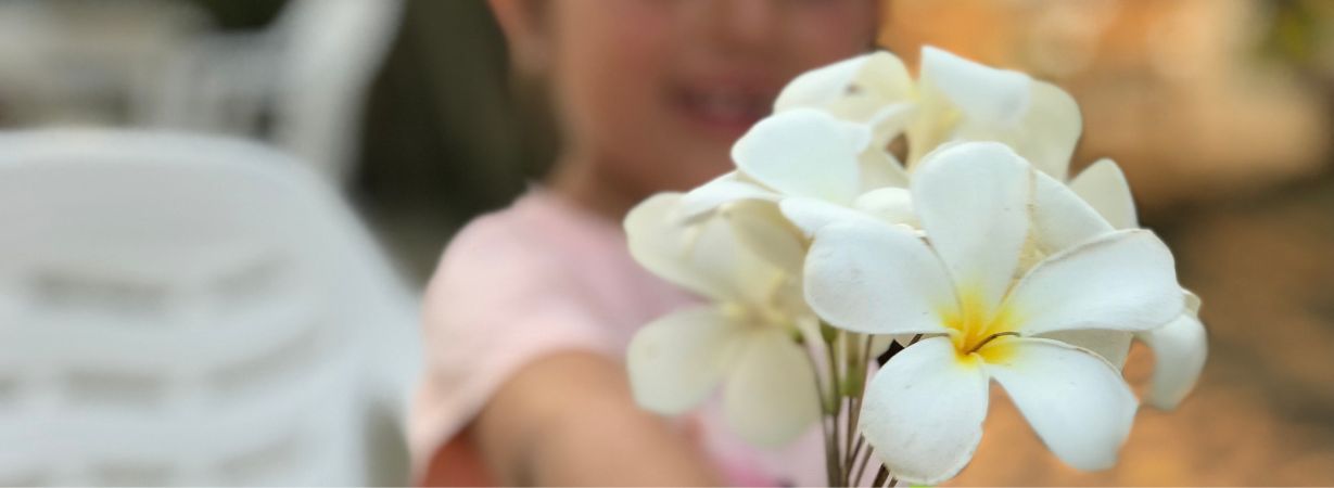 Mädchen mit Blumen, das verträumt in die Ferne blickt, repräsentiert die einzigartige Wahrnehmungswelt autistischer Kinder.