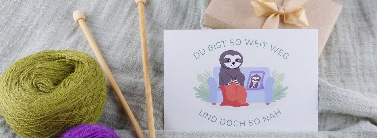 Postkarte mit Faultier-Oma, die das Bild ihres Enkelkindes betrachtet – ideal zur Stärkung des Kontakts zum Enkel