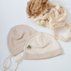 Zwei Frühchen Mützen in Beige, daneben Rohbaumwolle in hellem Braun