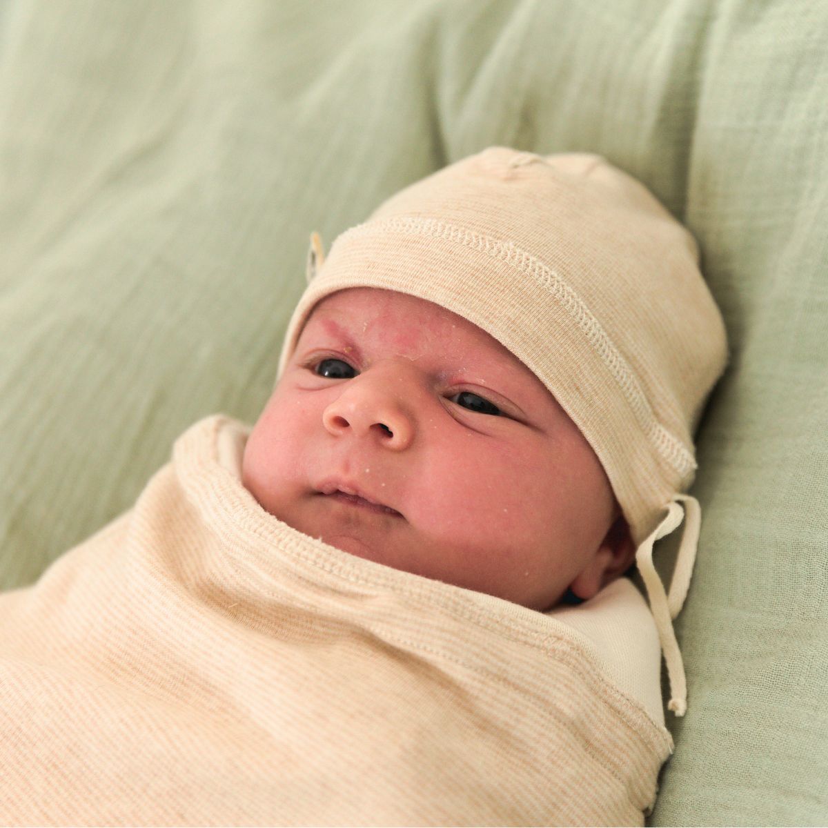 Frühchen mit Bio Mütze aus Pima Baumwolle auf weicher grüner Decke