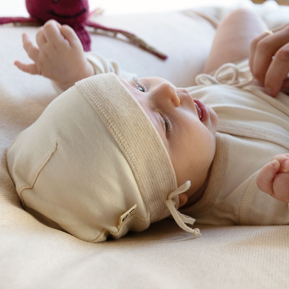 Frühchen Mütze in Beige aus weicher Pima Baumwolle, getragen von einem Baby mit sichtbarem Zugband