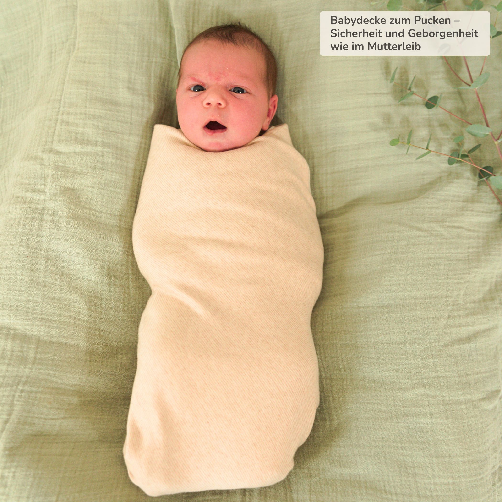 Baby in Bio Babydecke aus Pima Baumwolle, sanft gepuckt und geborgen auf grünem Tuch