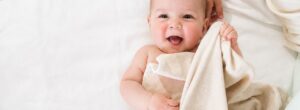 Baby nachts richtig anziehen – Baby liegt mit leichter Decke für warme Sommernächte