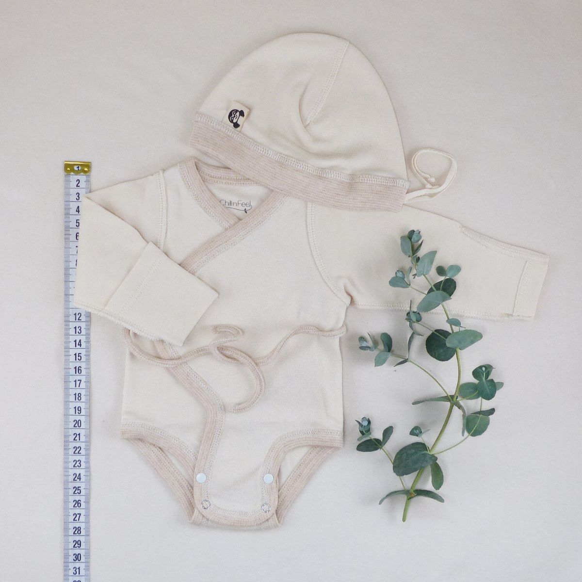 Frühchenkleidung Größe 44 – naturbeiges Set aus Wickelbody und Mütze, aus GOTS-zertifizierter Bio-Baumwolle, liebevoll inszeniert mit Maßband und Eukalyptuszweig