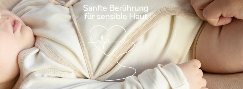 Frühchen in weichem Wickelbody aus Pima Baumwolle mit Herzgrafik und EKG-Symbol als Zeichen für sanfte Berührung bei sensibler Haut