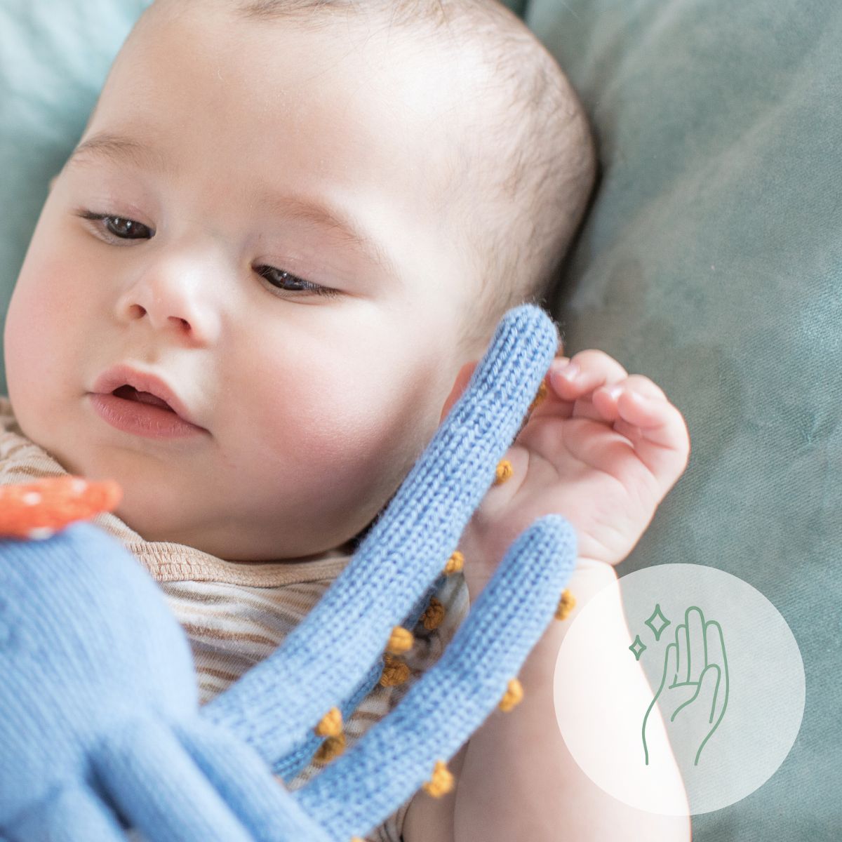 Baby spielt mit hypoallergenem, gestricktem Kuscheltier in Blau