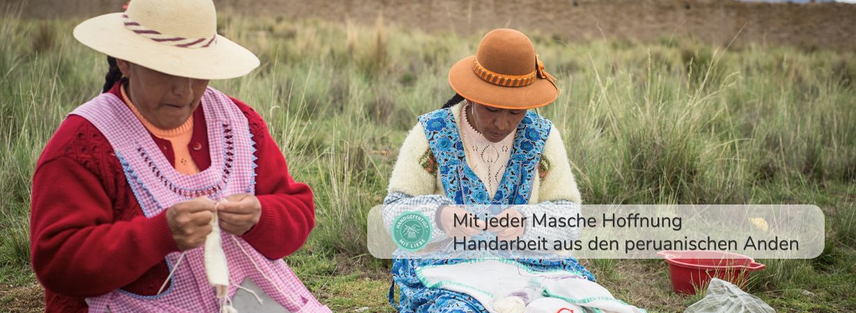 Zwei peruanische Frauen stricken im Grasland von Hand an gestrickten Kuscheltieren – faire Handarbeit aus den Anden.