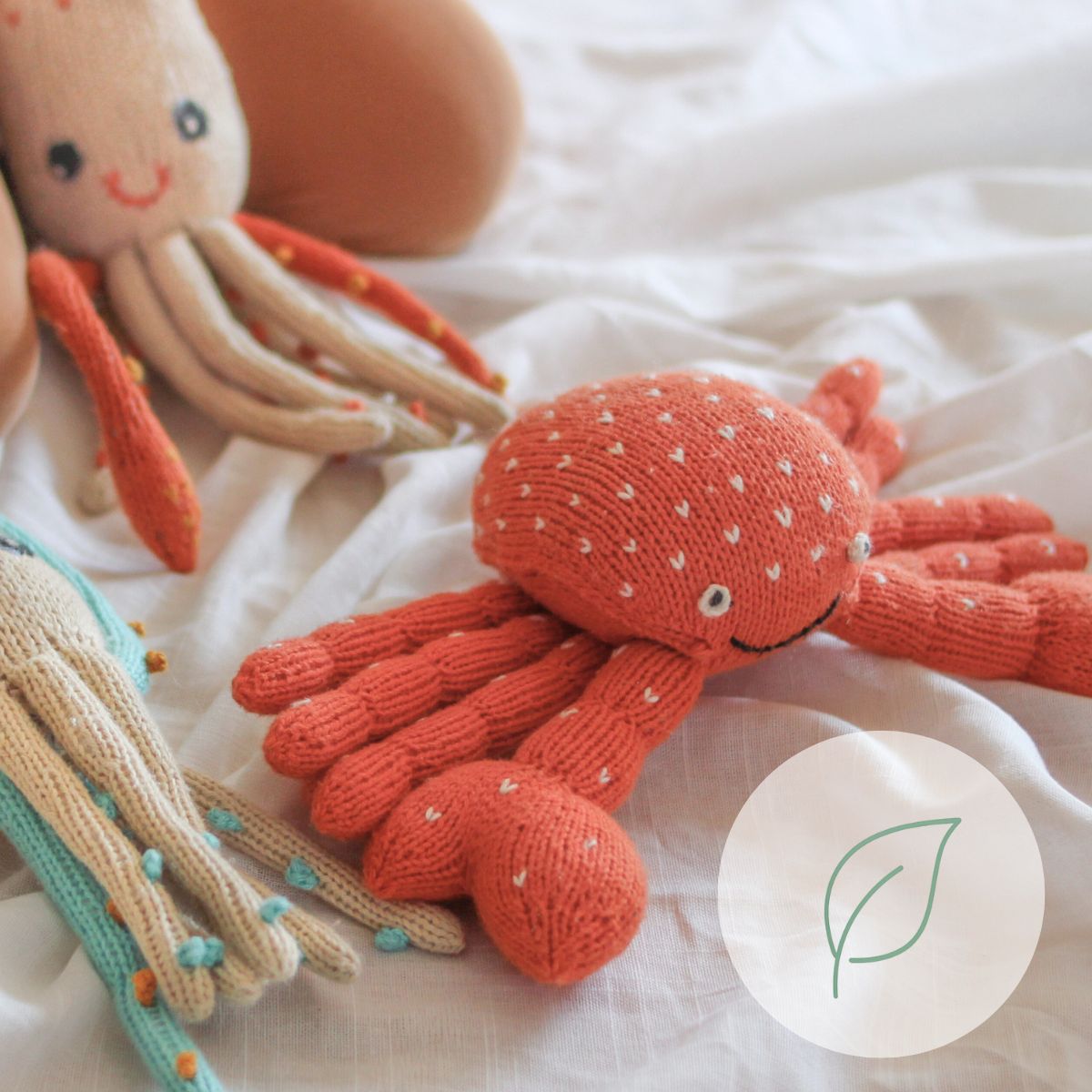 Vegane gestrickte Kuscheltiere wie Krabbe und Tintenfisch auf weißem Stoff