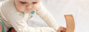 Baby trägt bei Neurodermitis im Sommer leichte Kleidung aus Pima-Biobaumwolle mit außenliegenden Nähten und integriertem Kratzschutz.