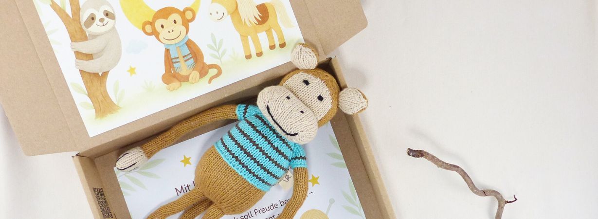 Handgefertigtes Kuscheltier personalisiert: Strickaffe aus Bio-Baumwolle in Geschenkbox mit personalisierter Postkarte im Waldtier-Design