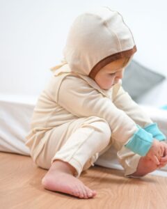 Baby im hautfreundlichen Overall aus Pima Baumwolle mit Mütze und Kratzschutzbündchen – idealer Schutz bei Neurodermitis und Kälte im Herbst und Winter.