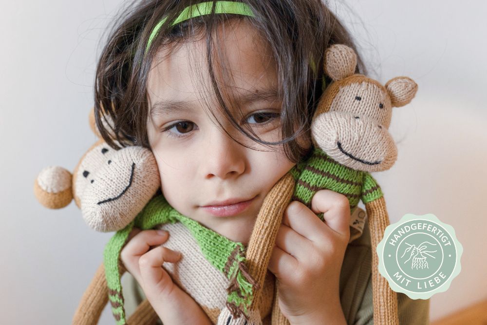 Kind kuschelt mit zwei handgestrickten Bio Kuscheltieren aus Baumwolle – hypoallergen, fair produziert und liebevoll von Hand gefertigt.