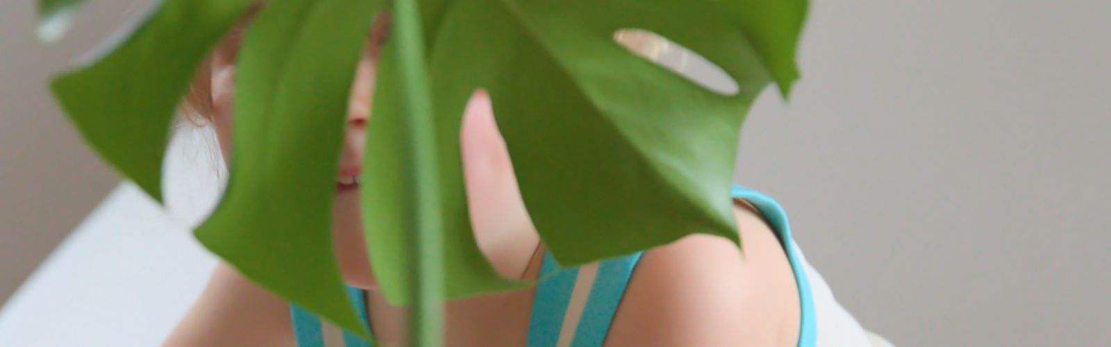 Kind im Alltag, das sich hinter einem Blatt vor Reizen schützt – Sinnbild für Neurodivergenz und sensorische Reizempfindlichkeit