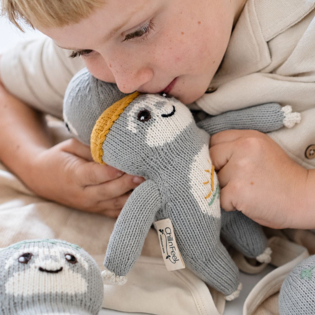 Kind kuschelt mit dem Baby Faultier Sonnen-Fauli aus weicher Bio-Baumwolle
