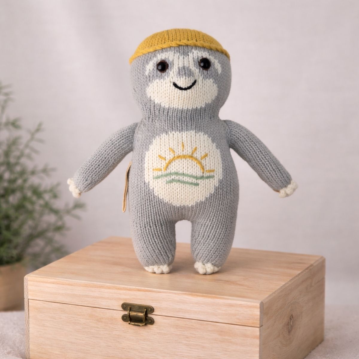 Handgestricktes Baby-Faultier Sonnen-Fauli auf Holzbox