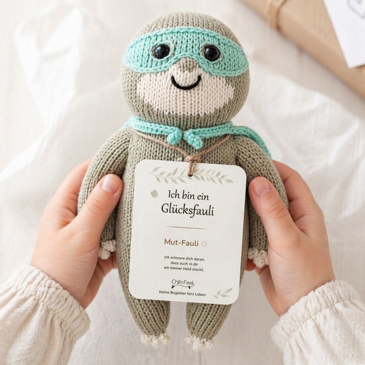 Bio Kuscheltier Faultier mit Hangtag in kleinen Kinderhänden als liebevolles Geschenk