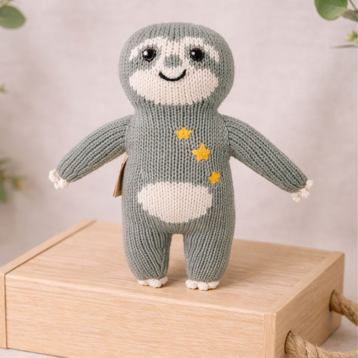 Handgestricktes Faultierbaby Sternen-Fauli mit aufgestickten Sternen auf Holzbox