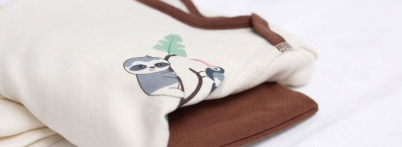 Gefaltete hautfreundliche Babykleidung aus Pima Baumwolle in Natur und Braun auf weißem Hintergrund – geeignet bei Neurodermitis Baby nachts