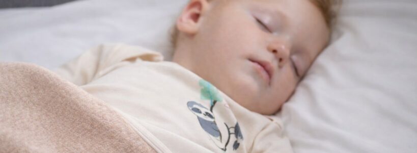 Schlafendes Baby in Neurodermitis Kleidung unter glatter Bio-Babydecke aus Pima Baumwolle