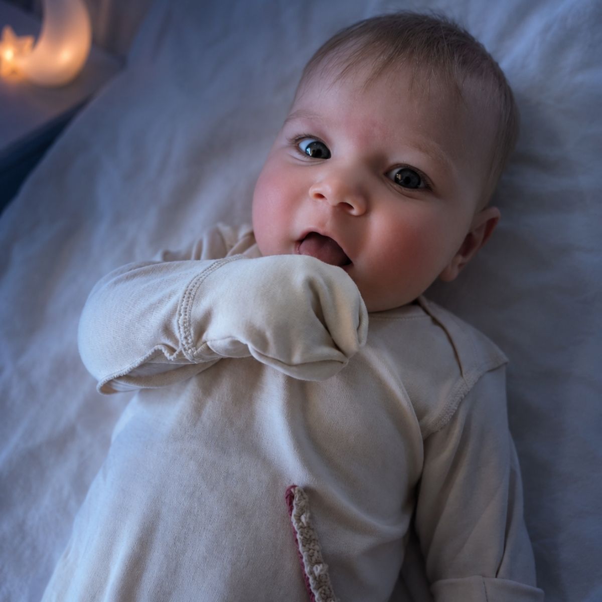 Baby mit Neurodermitis Kleidung und Kratzschutz in ruhiger Nachtatmosphäre