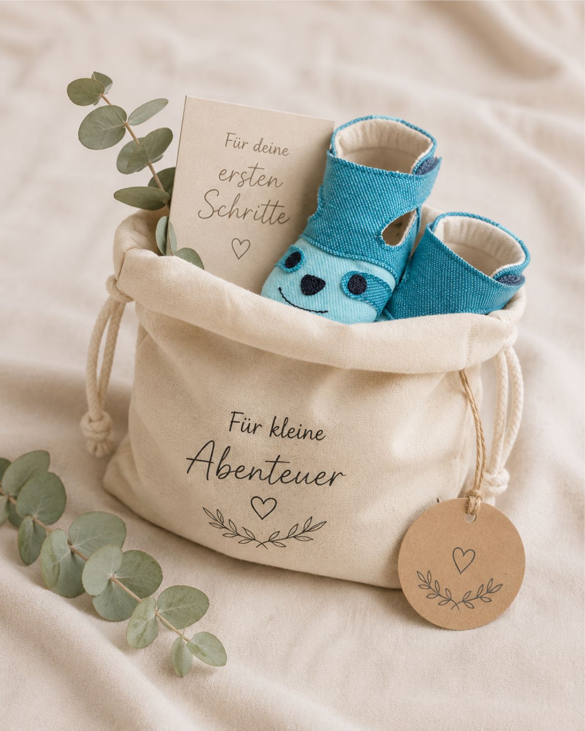 Babygeschenk im Stoffbeutel mit ersten Babyschuhen und Grußkarte verpackt