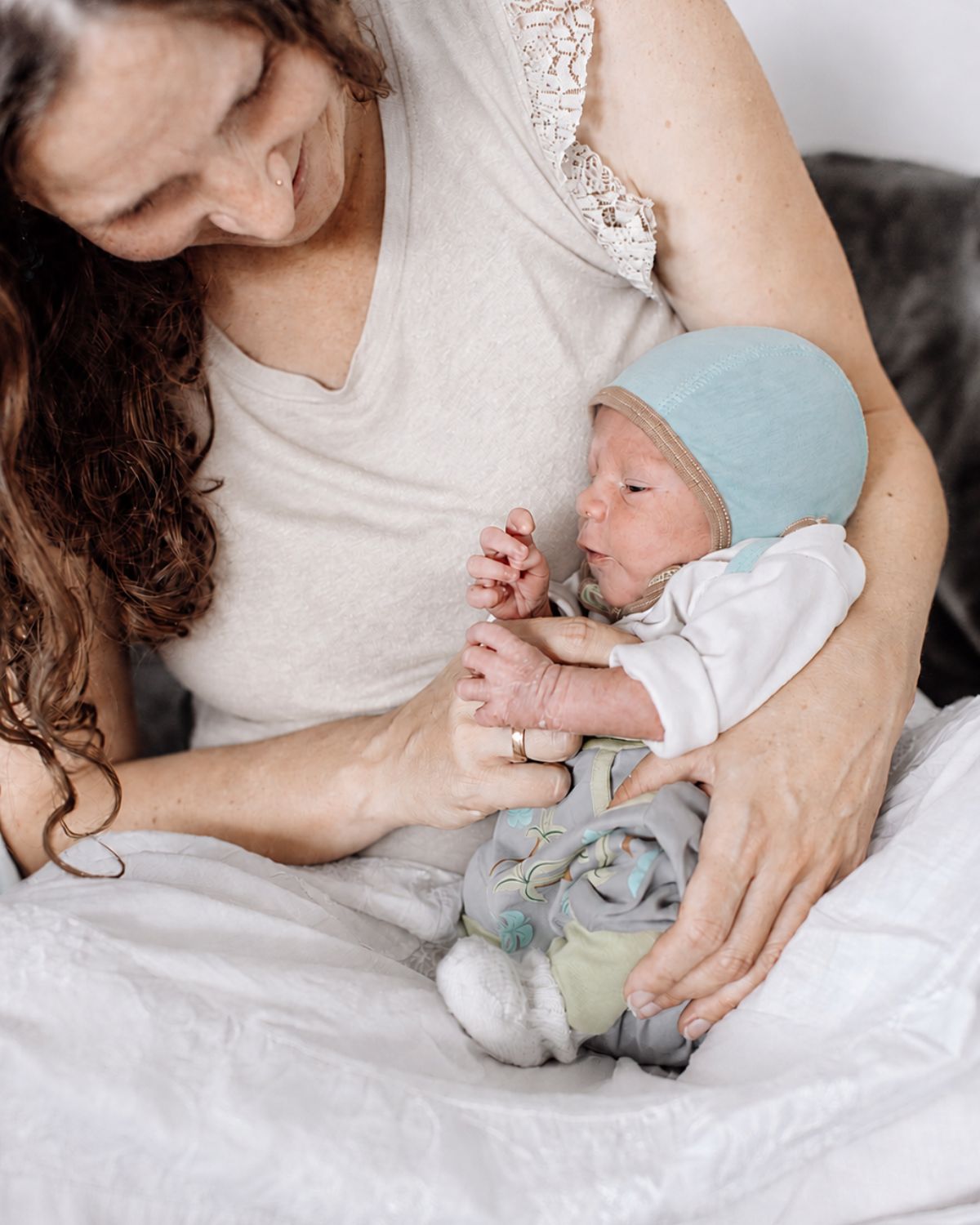 Mama hält ihr September Baby mit leichter Mütze aus Pima Baumwolle auf dem Arm