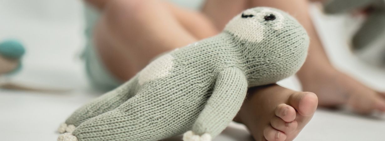 Kind mit einem gestrickten Faultier als Sinnbild für Geborgenheit bei Neurodermitis und psychischer Belastung.