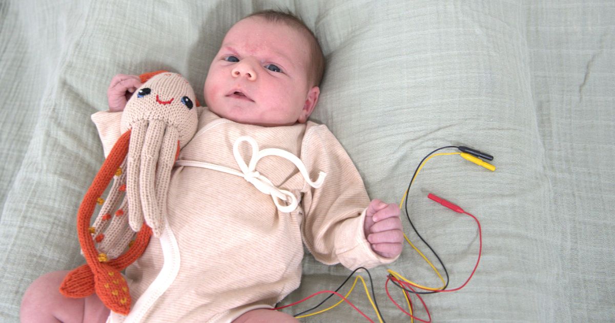Baby trägt einen naturfarbenen Frühchen Wickelbody mit überlappender Vorderseite und Bindeband