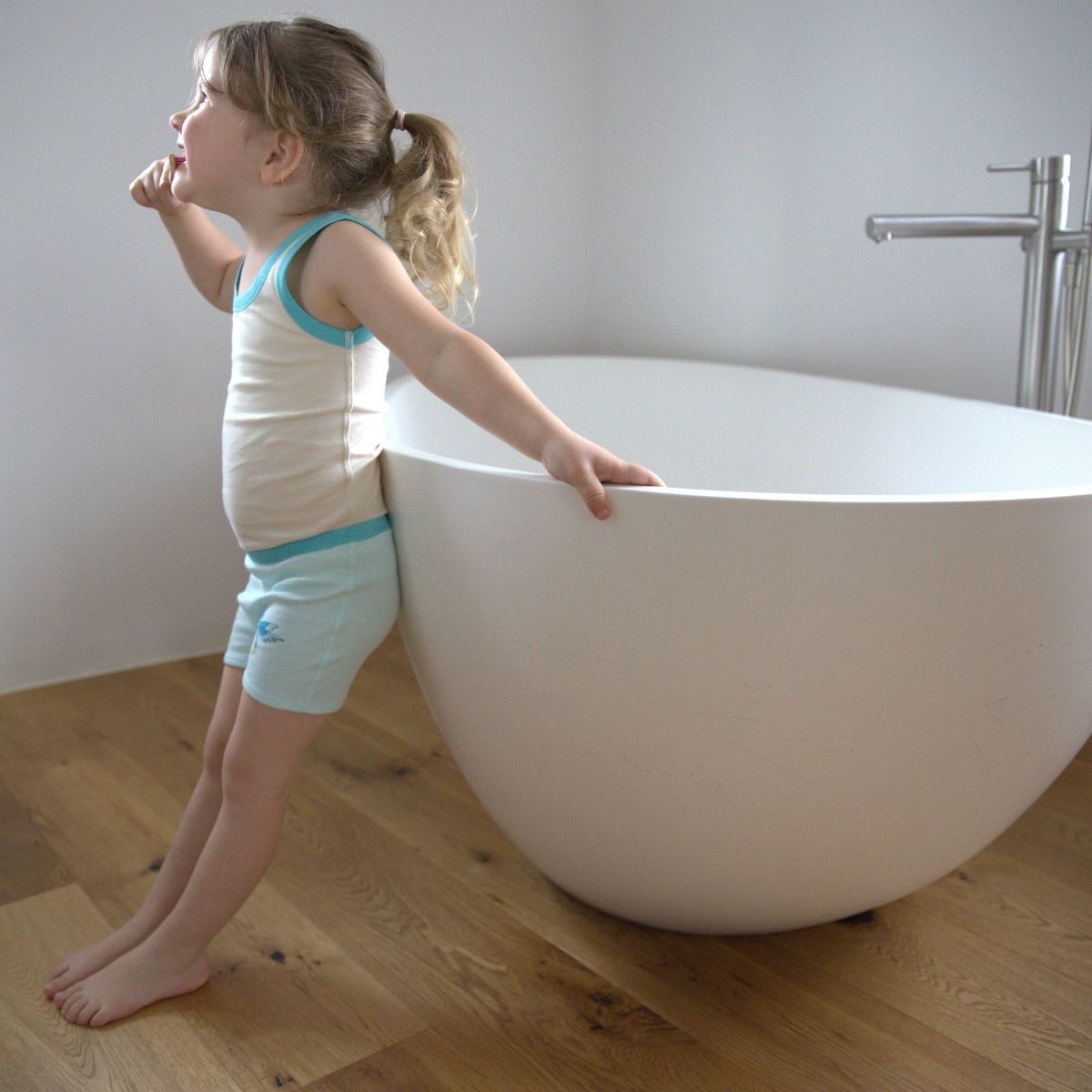 Mädchen trägt eine weiche Mädchen-Unterhose mit hohem Bund und bewegt sich entspannt neben einer Badewanne