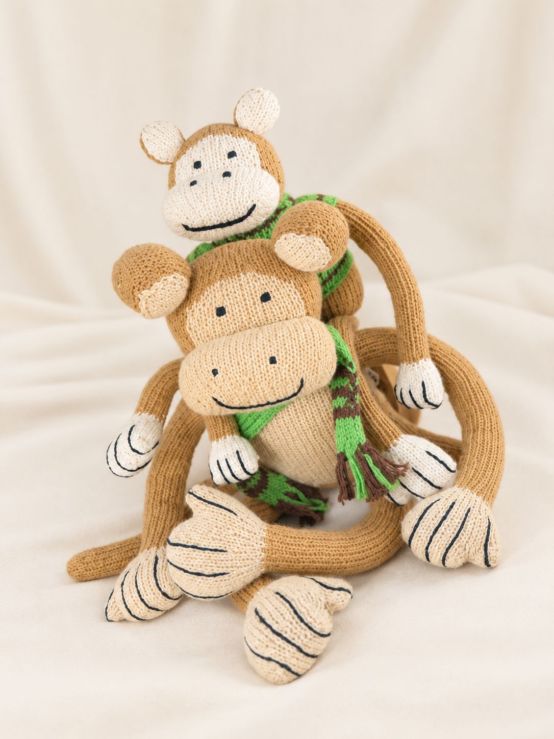 Zwei handgestrickte Affen in unterschiedlichen Größen sitzen zusammen